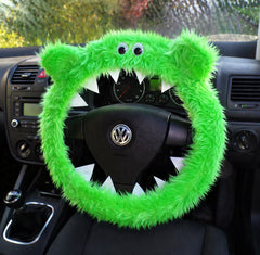 Handmade lime green monster steering wheel cover with googly eyes and white felt teeth on a black car steering wheel.
